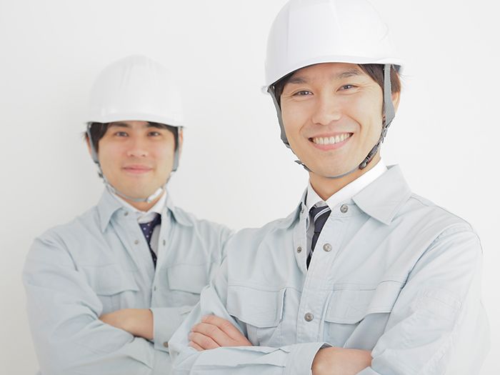 腕を組み微笑む作業着を着た男性２人